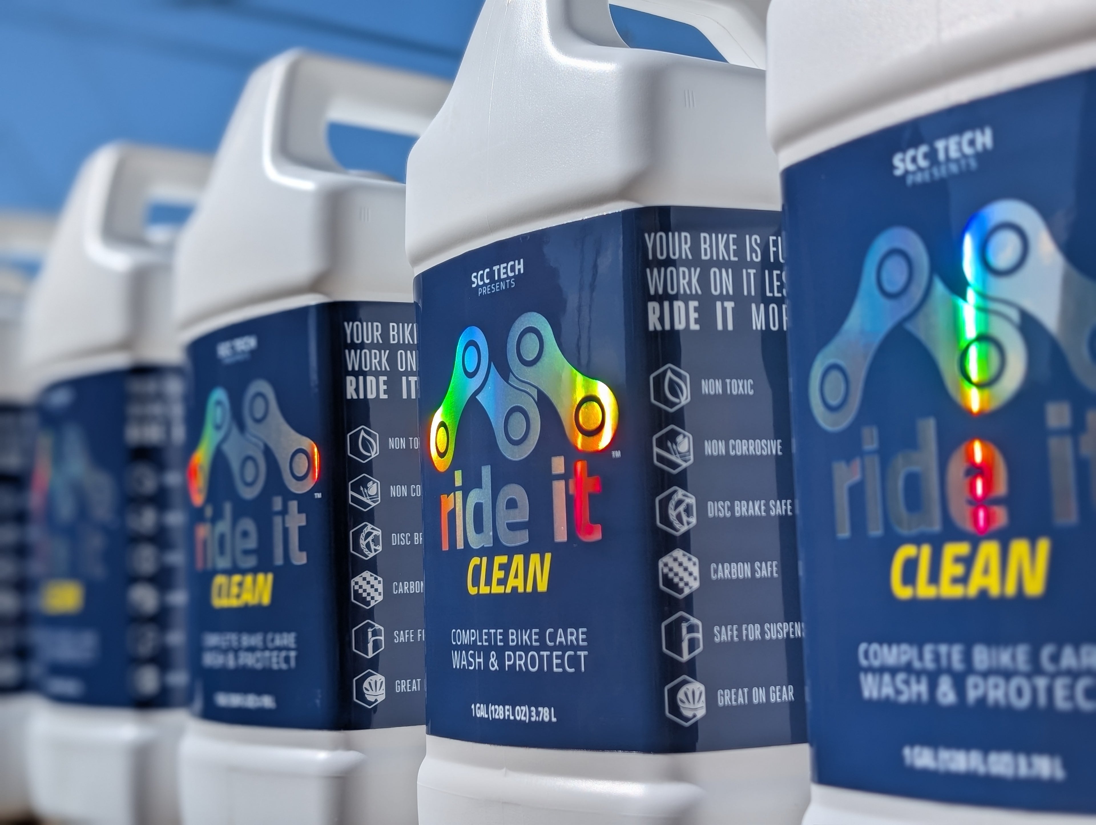 One-gallon container of Ride It Clean, a complete bike care wash and protect solution presented by SCC Tech. The white jug with a blue label features a bicycle chain link graphic and bold white and yellow text. The label highlights its purpose as a bike cleaning product designed to protect and clean bike surfaces. The container is 1 gallon (128 fl oz / 3.78 L), making it suitable for long-term bike maintenance needs.